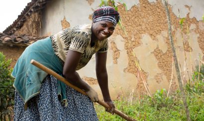 A smiling woman farmer tills her land