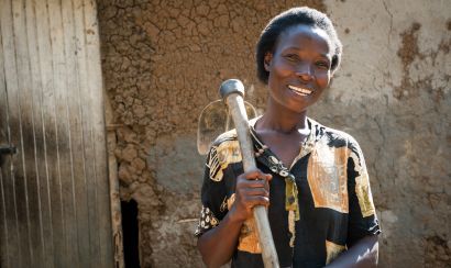 A farmer in Kenya stands holding her jembe