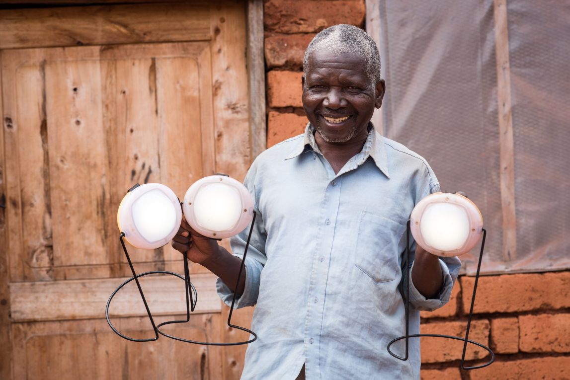 A farmer holding three solar lights